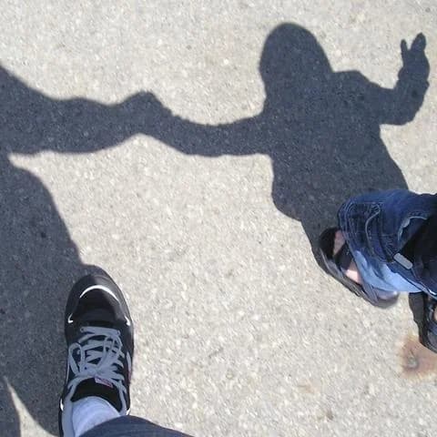 Illustration: the shadow of an adult and a child holding hands, cast on a pavement.